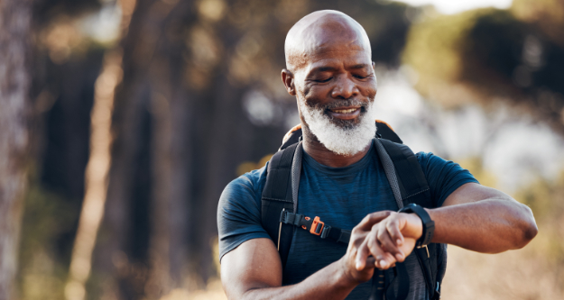 Man looking on his watch while hiking trough nature. - StayWild Outdoor